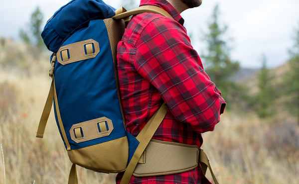 A profile shot of a person wearing the Guide's Pack with the optional padded hip belt.